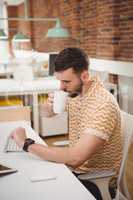 Male executive checking time while having coffee