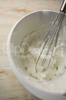 High angle view of wire whisk and whipped cream in bowl