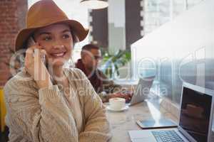 Woman with laptop talking on phone at counter