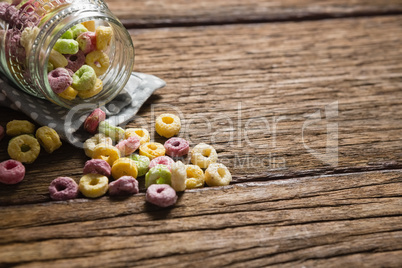 Scattered cereal rings from jar on wooden table