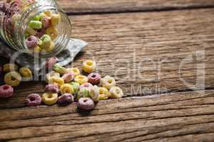 Scattered cereal rings from jar on wooden table