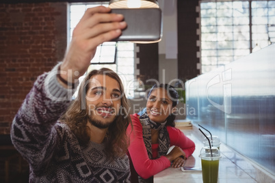 Man with friend taking selfie in cafe