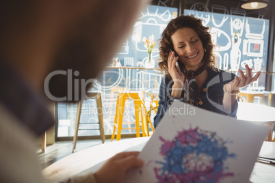 Woman with man talking on phone in cafe