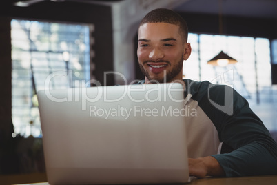 Smiling man using laptop in cafe