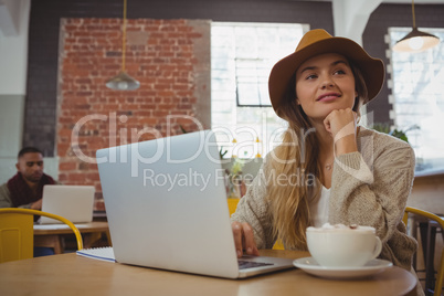 Thoughtful woman with laptop looking away