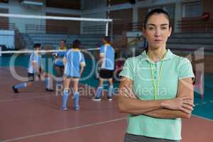 Portrait of coach by volleyball players at court