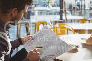 Businessman having coffee while reading newspaper