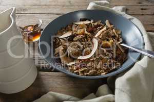 Bowl of breakfast cereal, honey and milk on wooden table