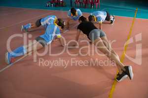 Full length of volleyball players warming up with coach