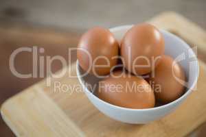 Brown eggs in bowl on cutting board