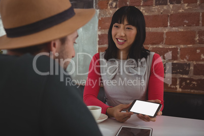 Woman showing phone to boyfriend at cafe