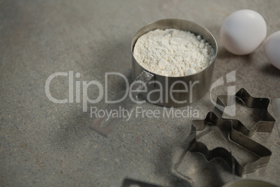 High angle view of flour in container with egg and pastry cutters