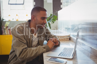 Businessman looking into laptop at counter