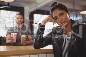 Portrait of woman with friend holding milkshake glasses in cafe