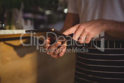 Mid section of waiter using tablet by counter