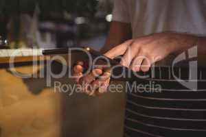 Mid section of waiter using tablet by counter