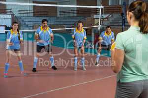 Coach playing volleyball with players