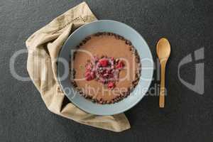 Chocolate syrup with fruits in bowl on black background