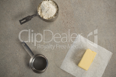 Butter on wax paper by strainer and flour in measuring cup