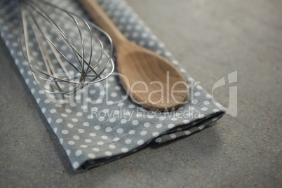 High angle view of wooden spoon with wire whisk on napkin