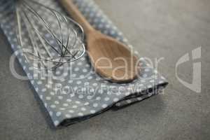 High angle view of wooden spoon with wire whisk on napkin