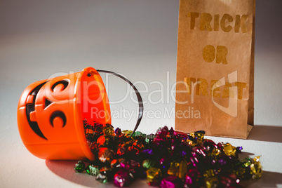Trick or treat text on paper bag by bucket and colorful chocolates