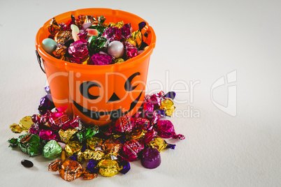 Bucket with various sweet food over white background during Halloween