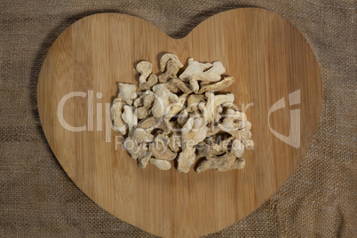 Overhead view of dried gingers on heart shape board over burlap
