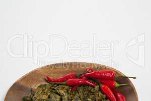 Overhead view of red chili pepper and dried kale in wooden plate