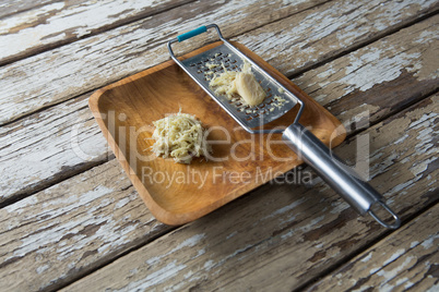 High angle view of steel grater and ginger in plate on table