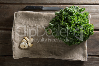 Fresh kale leaves with garlic on napkin at table