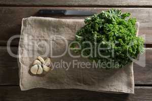 Fresh kale leaves with garlic on napkin at table