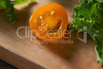 Fresh kale leaf and tomato slices on cutting board