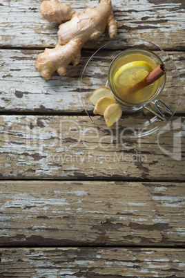 Overhead view of cinnamon and lemon in ginger tea on weathered table