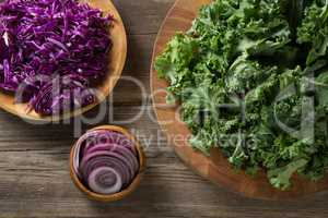 Fresh kale leaves with red cabbage and onion on table