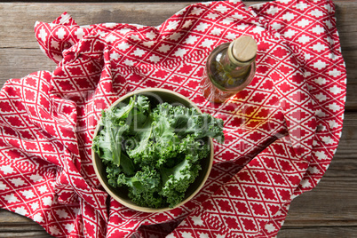 Fresh kale leaves with oil bottle and patterned fabric