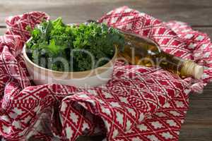 Fresh kale with oil bottle and fabric on table