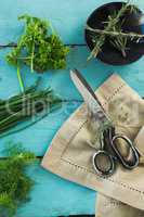 Various herbs, scissors and napkin on wooden table