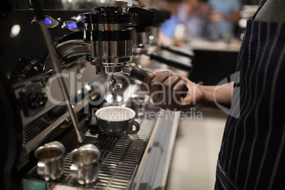 Mid section of waiter making cup of coffee
