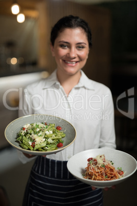 Portrait of smiling waitress holding food in bowl
