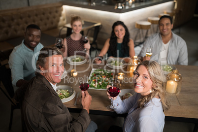 Happy friends having red wine while dining