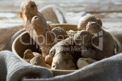 Close up of fresh gingers in bowl on burlap