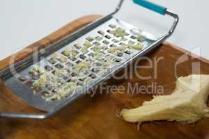Close up of steel grater and ginger on wooden plate
