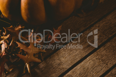 Cropped image of pumpkin with autumn leaves on table