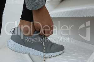 Female athlete tying shoelace on stairs