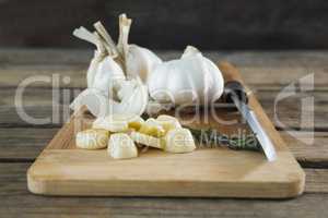 Garlics, rosemary and knife on chopping board