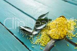 Raw organic yellow rice and curry leaves on wooden table
