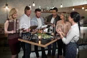 Group of friends giving order to waitress