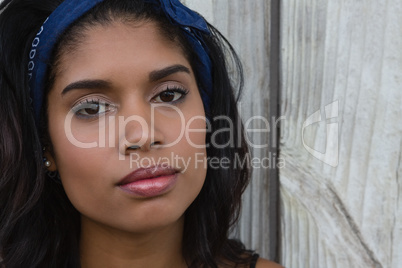 Confident young woman against wooden wall