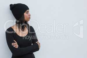Thoughtful woman with arms crossed against white wall